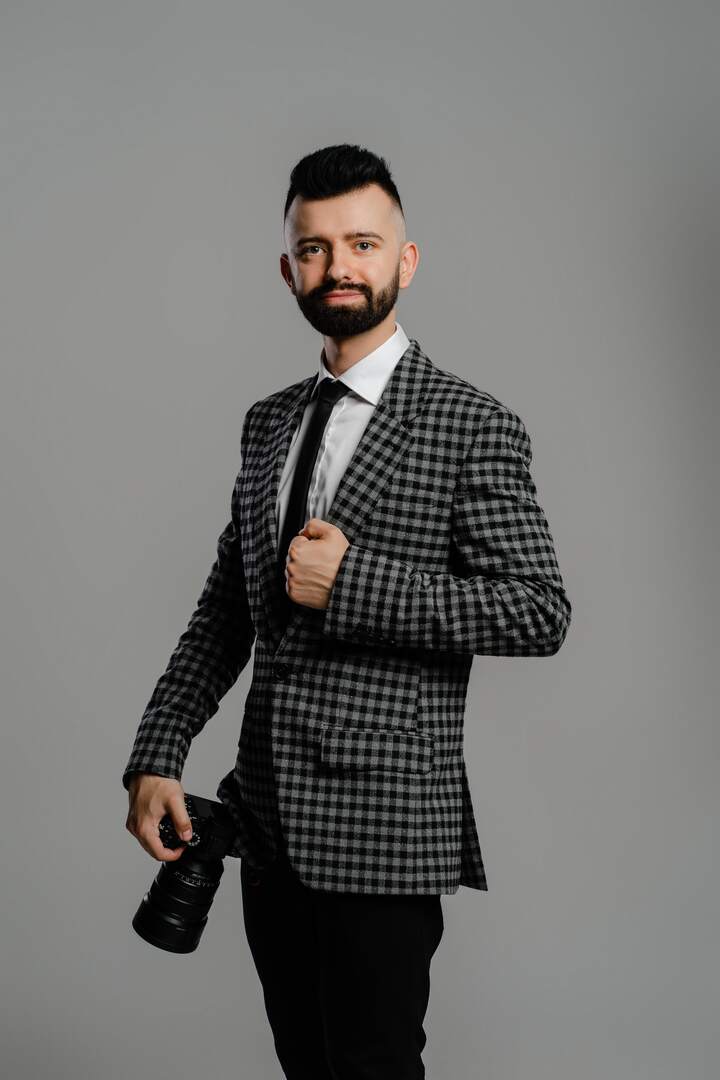 Jakub Ślaga w marynarce w kratę z aparatem